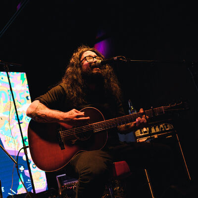 Man sitting on stage playing guitar